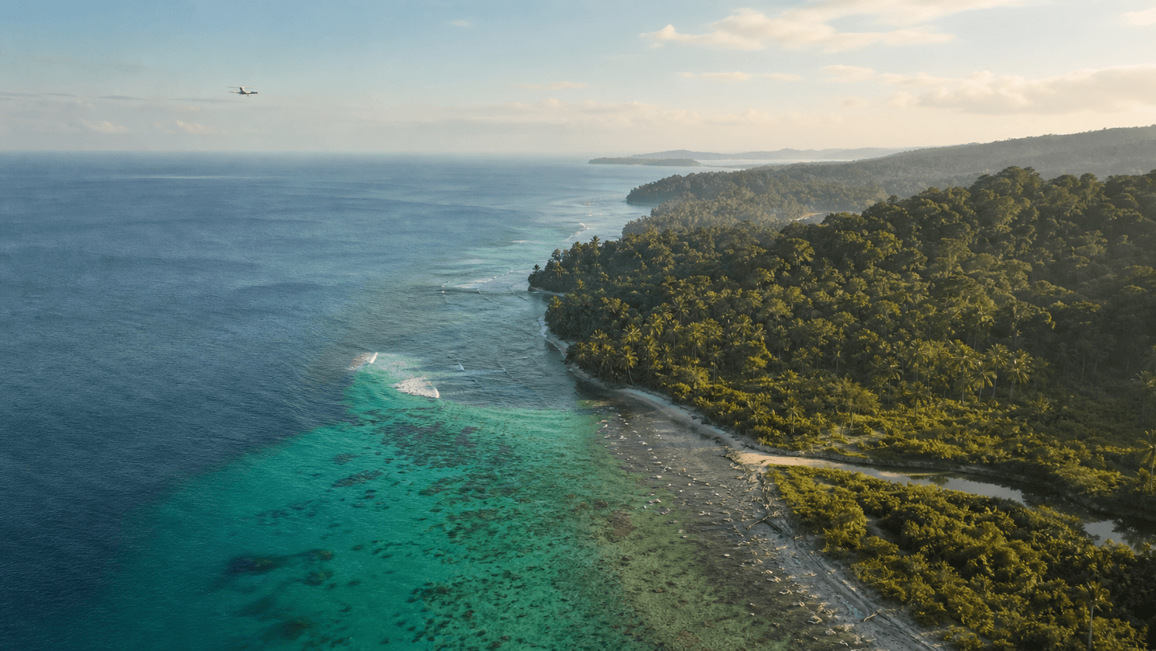 Pemandangan udara pesisir Mentawai yang cerah dengan terumbu pirus, hutan hujan, dan pantai terpencil